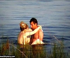 Tanned hung stud fucks a naked blonde in a lake